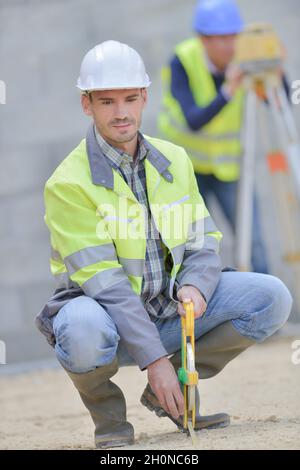 Builders Using Measure builders using measuring tools outdoors in a construction site Stock ...