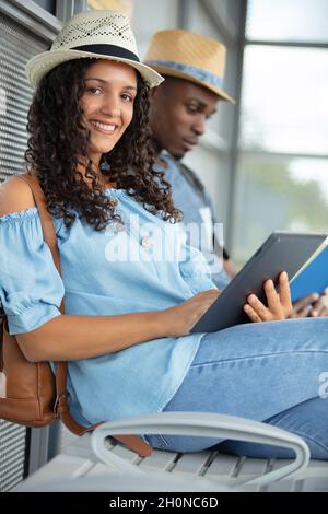 people waiting for public transport reading tablet and book Stock Photo