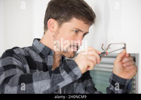 handyman installing window curtain rod support on the wall Stock Photo