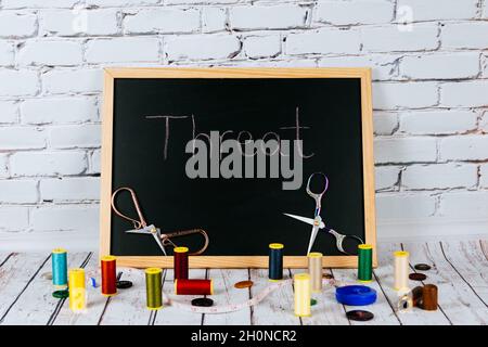 Accessories for needlework  on a wooden table and on a blackboard background Stock Photo