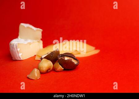 Camembert cheese with honey and macadamia nuts on a red background. Stock Photo