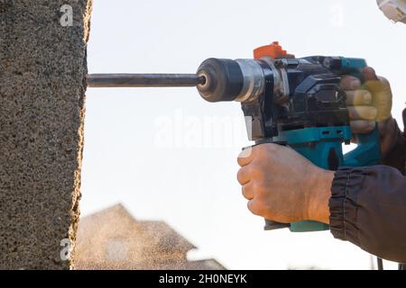 A male installer works with a hammer drill. Construction works Stock Photo