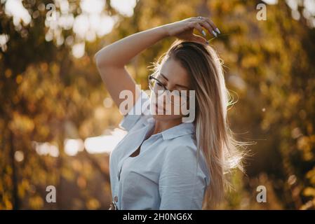 Young Caucasian lady wearing a shirt with accessories and optical glasses posing outdoors Stock Photo