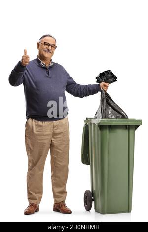 Arab man throwing a plastic waste bag in a bin with a pile of bags ...