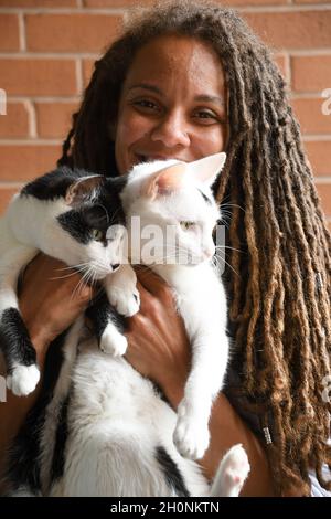 Woman smiles while holding two cats Stock Photo