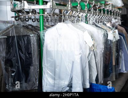 Rack of clean clothes hanging on hangers at dry-cleaning Stock Photo - Alamy