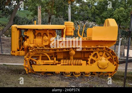 a large yellow agricultural crawler tractor without a driver stands still Stock Photo