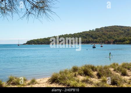 A stand up paddle boarder and boats at anchor. Stock Photo