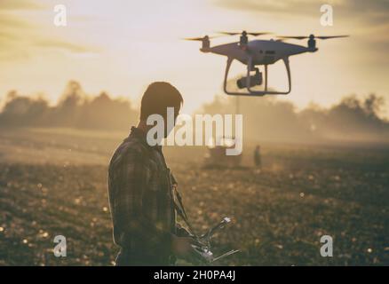 Attractive farmer navigating drone above farmland. High technology innovations for increasing productivity in agriculture Stock Photo