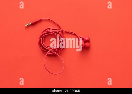 Red headphones with rolled wire, on a red background Stock Photo