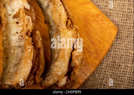 Small fried fish on a wooden board, close-up, selective focus Stock Photo