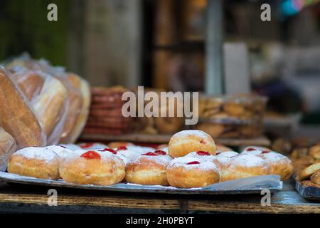 Fresh donuts stuffed with jam coated in powdered sugar, ready for sale at the Mahane Yehuda market on Hanukkah Stock Photo