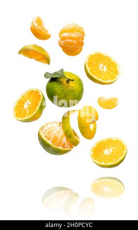 Fresh ripe green mandarine with leaf falling in air. Cut, peeled, slices and whole green tangerine isolated on white background with clipping path. Food levitation concept Stock Photo
