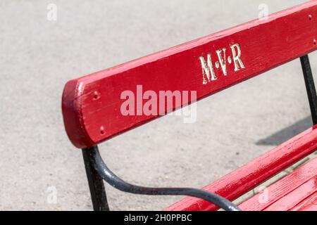 Red Wooden Slatted Bench Seat With The Initials Carved In the Back For the Moors Valley Miniature Railway Stock Photo