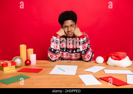 Photo of young brunet guy sit work wear holiday sweater isolated on red color background Stock Photo