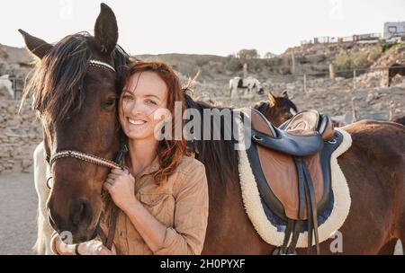 Young farmer woman playing with her horse at farm ranch - Focus on female face