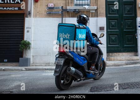 Valletta, Malta - October 9, 2021: Wolt deliveryman riding a motorbike on the streets of Valletta, Malta. Stock Photo
