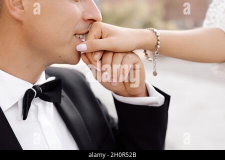 Crop photo of unrecognizable man in wedding suit kissing hand of his bride in wedding dress tenderness, wedding day concept. Happy moments Stock Photo