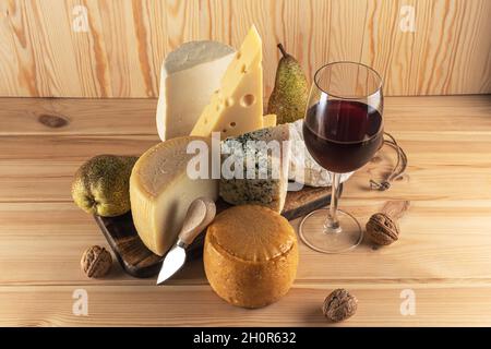Various kind of cheese with glass of wine on wooden table. Cheese background. Stock Photo