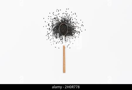 Black sesame seeds in a spoon isolated on white. Flat lay. Top view Stock Photo