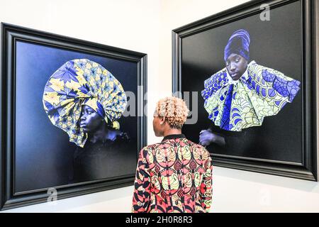 Somerset House, London, UK. 14th Oct, 2021. Gallery owner Carole poses with Angèle Etoundi Essamba, Renaissance florale, 2019, and Deploiment, 2019, by the same artist, Galerie Carole Kvasnevski. 1-54 is the leading international art fair dedicated to contemporary art from Africa and its diaspora. It returns to London for its 9th edition, presenting work from 48 leading international galleries from 23 countries. Credit: Imageplotter/Alamy Live News Stock Photo