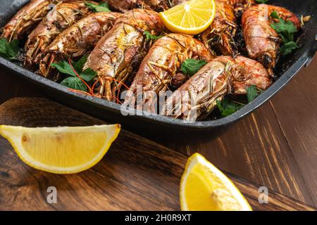 Fried shrimps on grill pan with fresh herbs and lemon slice. Seafood background. Stock Photo