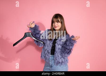 Blogger teaches classes on creating stylish image. young pretty woman holds empty clothes hanger on pink background in studio. . High quality photo Stock Photo