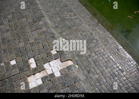 Missing tiles in a grey mosaic abandoned swimming pool Stock Photo