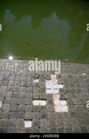 Missing tiles in a grey mosaic abandoned swimming pool Stock Photo