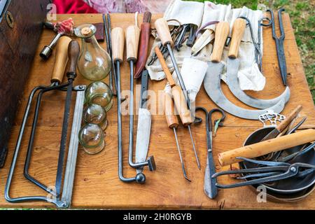 Medieval living history display. Barber surgeons tools, including amputation knife, saws and leeching bottles displayed on a wooden table. Stock Photo