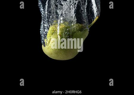 Fresh green pear in water splash isolated on black background. Minimal food concept. Stock Photo