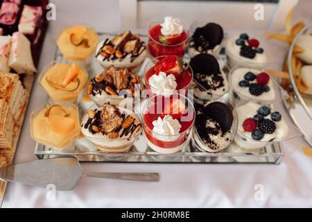 Several varieties of cakes in baskets on plates, decorated with butter cream or curd cream with fruits and berries, top view, concept of food in holid Stock Photo