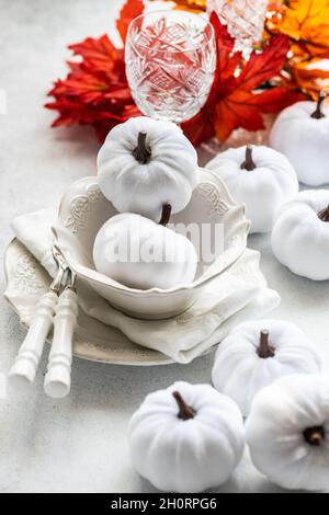 Autumnal Thanksgiving place setting on a table with pumpkin ornaments and leaf decorations Stock Photo
