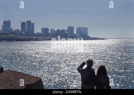 Rear view of a man and his teenage daughter looking at city skyline, Mar del Plata, Buenos Aires Province, Argentina Stock Photo