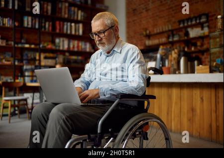 Adult disabled man in wheelchair using laptop Stock Photo
