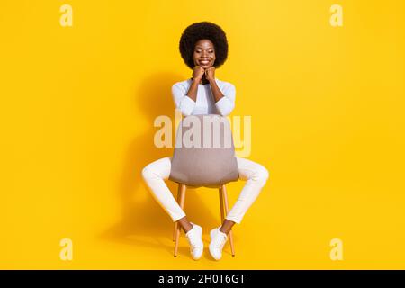 Full size photo of impressed cute brunette short hair lady hands chin wear white pullover trousers sneakers isolated on yellow background Stock Photo