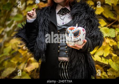 woman is holding terrible painted melon on Halloween. witch holds his head. Stock Photo