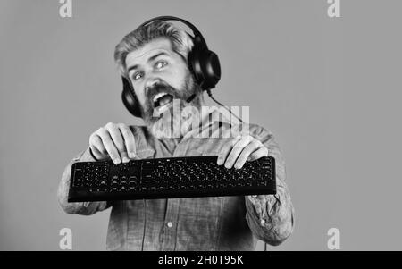 Superior performance. Graphics settings pushed to limit. Play computer games. Man bearded hipster gamer headphones and keyboard. Gaming addiction Stock Photo