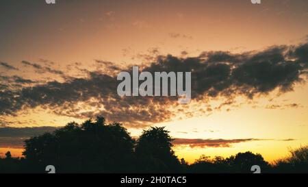 Close shot of blue sky and sun background with clouds. Landscape of a cloudy sunset with silhouettes of trees. Sunset cityscape silhouette contrast vi Stock Photo