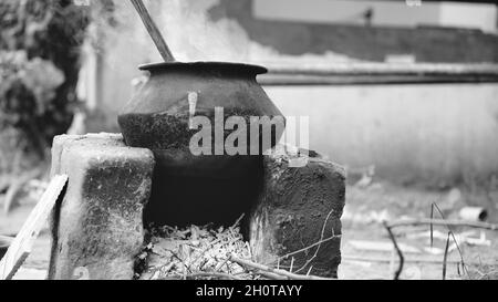 Water or something being boiled on a aluminum pan kept on a earthen oven with wood as fuel at a village in India. Stock Photo