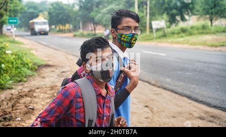 10 October 2021 Reengus, Rajasthan, India. Indian children with mask, going to school in the morning, first day, caring bouquet of flowers for the tea Stock Photo