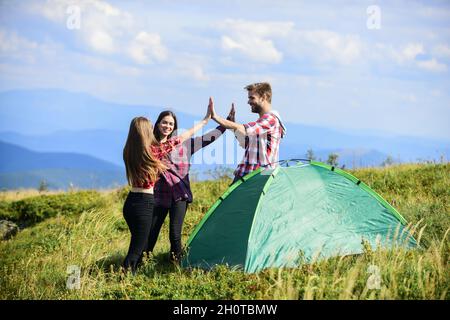 Well done. Camping gear. Camping tent. Good job. Teamwork concept. Hiking activity. Friends set up tent on top mountain. Camping equipment. Weekend in Stock Photo