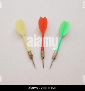 Yellow red and green darts lie on a light background. Close-up photo. Stock Photo