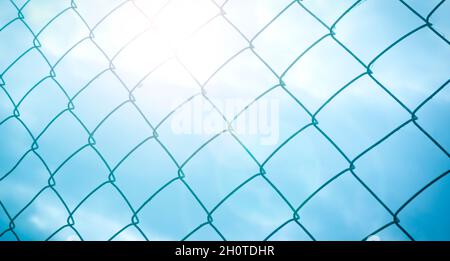 The texture of the metal mesh-netting against the background of the pastel colors of the sky. Beautiful abstract background. Stock Photo