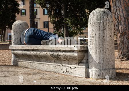 Homeless person sleeping on park bench in Rome, Italy Stock Photo