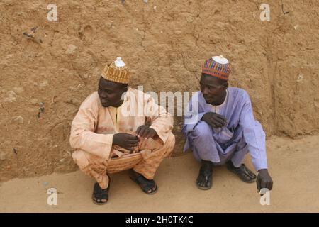 Men chatting in Shinkafi, a town in Zamfara state in northern Nigeria. Most of the people who live her are poor, living below US$1 a day. Hausa is spoken as the first language of the state, which is also the first state to have introduced Muslim sharia law. 'Farming is our pride' is the slogan of the state, which is largely agricultural. April 12, 2008. Stock Photo