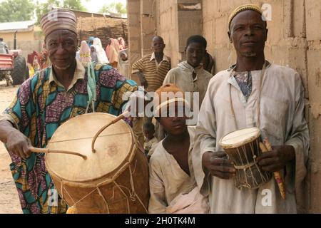 Street musicians in Shinkafi, a town in Zamfara state in northern Nigeria. Most of the people who live her are poor, living below US$1 a day. Hausa is spoken as the first language of the state, which is also the first state to have introduced Muslim sharia law. 'Farming is our pride' is the slogan of the state, which is largely agricultural. April 12, 2008. Stock Photo