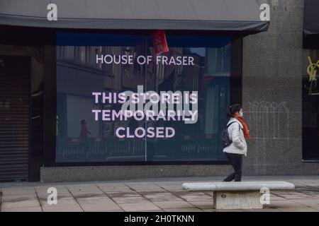 A woman with a face mask walks past a Closed store sign at House of Fraser department store on Oxford Street during the nationwide coronavirus lockdown in England. 10th February 2021. Stock Photo