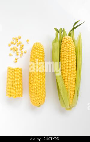 ear of corn with green leaves, peeled cob and seed isolated on white background, fresh maize, top view Stock Photo