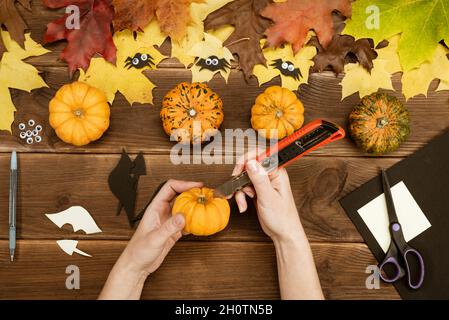 We make gifts for Halloween. Making a funny bat out of a small yellow pumpkin. Halloween party decor. DIY instruction. Step by step guide. Step 5. Stock Photo